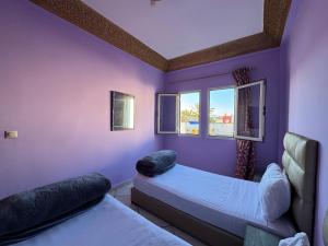 a purple room with two beds and a window at Dar Bennis 2 in Rabat