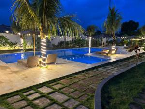a swimming pool at night with chairs and a palm tree at Kotoa Villa 68 in Nusa Dua