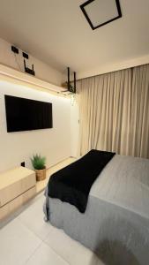 a bedroom with a bed and a flat screen tv at Flat em Carapibus moderno e aconchegante in Conde +3 photos