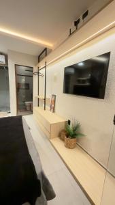 a bedroom with a large tv on the wall at Flat em Carapibus moderno e aconchegante in Conde