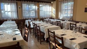 a dining room with white tables and chairs and windows at Hotel Chalet Seggiovia in Pontechianale