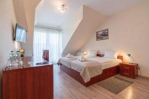 a bedroom with a bed and a desk with a television at Pensjonat Perła Pienin in Grywałd
