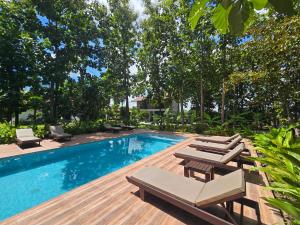 a swimming pool with chaise lounge chairs next to a wooden deck at Anusorn Villas & Garden Oasis - Peaceful Chiang Mai Hideaway in Ban Ton Chok