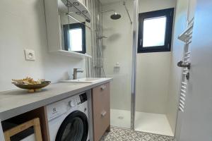 a bathroom with a washing machine and a shower at Le Clos des Marmuzots parking & garden in Bayeux