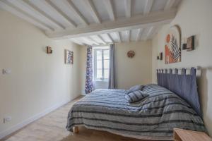 a bedroom with a bed with a striped blanket at Les Colibris little house in the city-center in Arromanches-les-Bains