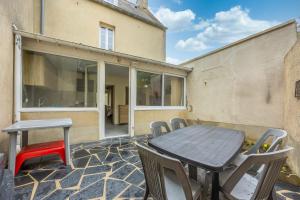a patio with a wooden table and chairs at Les Colibris little house in the city-center in Arromanches-les-Bains +10 photos