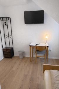 a living room with a table and a television on a wall at Hotel Haus Schwan Köln in Cologne
