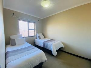 two beds in a small room with a window at The Grey Ivory in Port Alfred