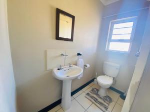 a bathroom with a white sink and a toilet at The Grey Ivory in Port Alfred