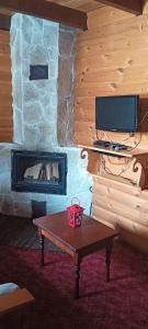 a living room with a fireplace with a table and a television at mezonetaki in Karpenisi