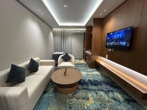 a living room with a white couch and a tv at فندق سويت فيو in Al‘Āriḑah