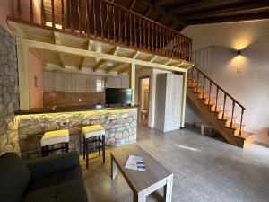 a living room with a kitchen and a counter with chairs at Alkionis Pool View Apartments in Lefkada