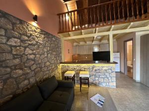 a living room with a couch and a stone wall at Alkionis Pool View Apartments in Lefkada