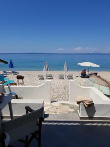 a beach with chairs and umbrellas and the ocean at Beachfront villa Ioanna in Kokkari