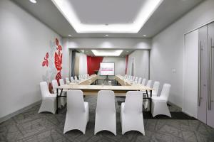 favehotel Sudirman Bojonegoro في Bojonegoro: قاعة اجتماعات مع طاولة طويلة وكراسي بيضاء