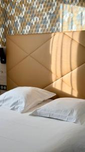 ein Schlafzimmer mit einem weißen Bett und einem braunen Kopfteil in der Unterkunft Hôtel Le Goëlo - Port de Paimpol in Paimpol