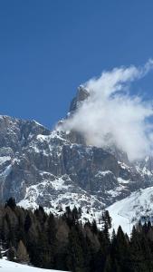 a mountain covered in snow with clouds on it at Dolomiti Nest in Tesero