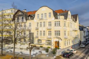 a yellow building on a street with cars parked in front at Hotel Alex an der Ahr in Bad Neuenahr-Ahrweiler