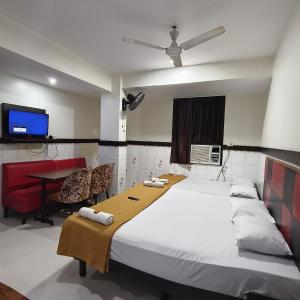 a bedroom with a bed and a desk and a tv at Sai Lodging And Boarding in Dombivli