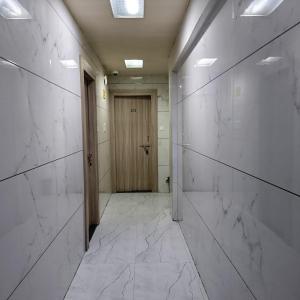 a hallway with white marble walls and a wooden door at Sai Lodging And Boarding in Dombivli +20 photos