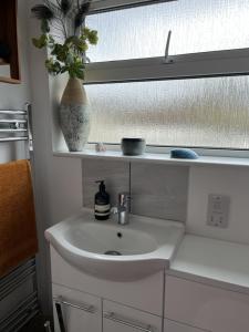 a bathroom with a white sink and a window at Retreat for Two in Shepton Mallet +4 photos