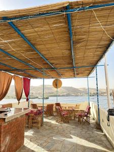 a patio with chairs and tables with a view of the water at Queen House in Aswan