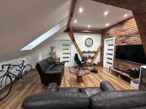 a living room with black leather furniture and a brick wall at PS5, VR2, Logitech racing-Apartmán pod Chočom in Leštiny
