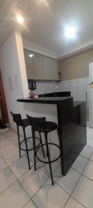 a kitchen with two black chairs and a counter at Ap no Turu, 10 min das praias in São Luís