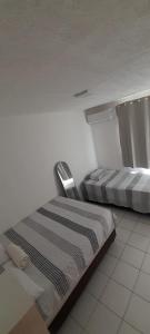 two beds in a white room with a window at Ap no Turu, 10 min das praias in São Luís