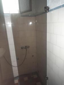 a shower in a bathroom with white tiles at Canela in Atlántida
