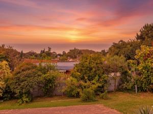 a sunset over a yard with trees and a fence at Da Vinci - Zur See in Ballito +1 photo