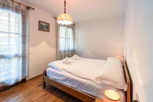 a bedroom with a bed with white sheets and a window at Casa Tre Corone, sulla strada per Cortina in Borca di Cadore
