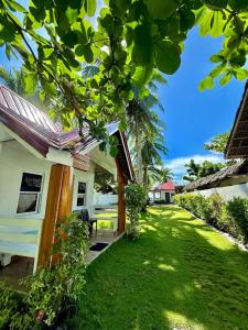 a house with a yard with green grass at Villa with Beachfront Access in Lalauigan