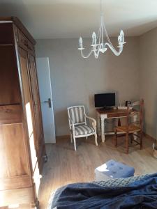 a bedroom with a desk and a chair and a chandelier at La Maison Bleue in Rosières