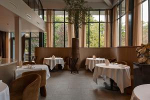 a restaurant with tables and chairs and windows at Hotel Gastronomique de Echoput in Apeldoorn