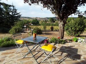 a table and two chairs with yellow cushions at La Maison Bleue in Rosières