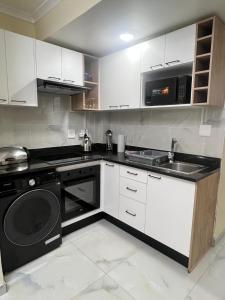 a kitchen with white cabinets and a stove and a dishwasher at The Oceanic 42 in Durban