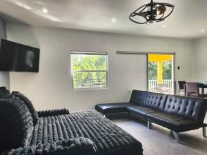 a living room with a black leather couch and a television at Tropical Tobago in Riseland