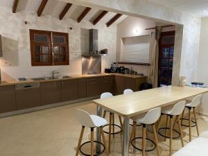 a kitchen with a wooden table and white chairs at Villa Soleil des Caraïbes in Gourbeyre