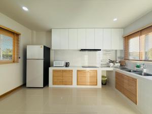 a kitchen with white cabinets and a refrigerator at House in HangDong in Hang Dong