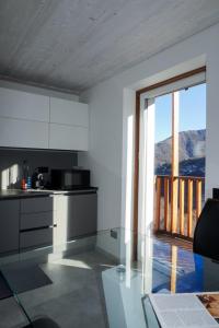 a kitchen with white cabinets and a large window at Graziosa, Casetta in Valgerola in Rasura