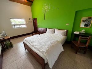 a bedroom with a green wall and a bed at Color Rainbow Home in Taimali