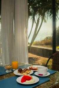 a table with plates of food and a cup of orange juice at Pousada Mirante dos Papagaios in Búzios