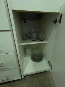 a white cabinet with some bowls and plates in it at Fully equipped studio apartments in Apóstoles