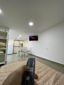 a person holding a remote control in a room at Fully equipped studio apartments in Apóstoles