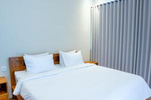 a bed with white sheets and pillows next to a radiator at Aditya House in Ubud +4 photos