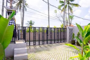 a black gate in a driveway with palm trees at Aditya House in Ubud