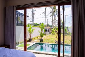 a bedroom with a view of a swimming pool through a window at Aditya House in Ubud