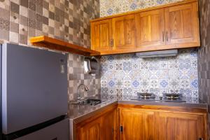 a kitchen with wooden cabinets and a refrigerator at Aditya House in Ubud