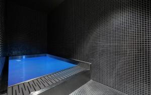 a shower with a blue tub in a black tiled room at Královské apartmány - Špindlerův Mlýn in Špindlerův Mlýn